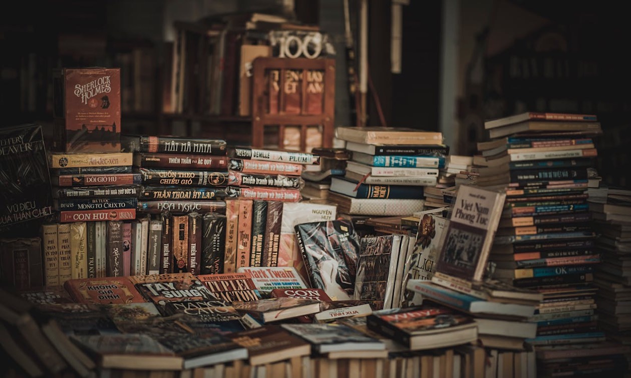 Libri impilati su un tavolo di legno con luce morbida, simbolo di tempo dedicato all'altro